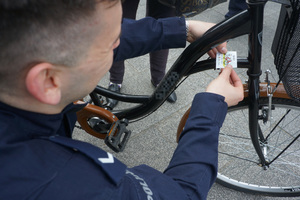 Policjant umieszcza naklejkę na rowerze