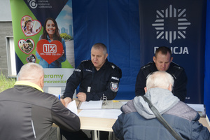 Uczestnicy akcji znakowania rowerów wypełniają stosowne dokumenty. Widoczni także policjanci