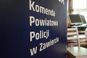 Częściowo widoczny baner z napisem Komenda Powiatowa Policji w Zawierciu