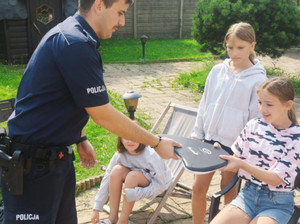 Policjant wręcza dzieciom upominki.