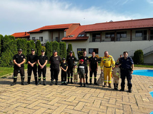 Zdjęcie przedstawia strażaków, policjanta i dzieci w mundurze.