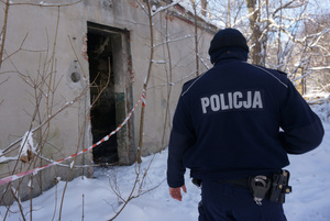 Na kolorowym zdjęciu widoczny dzielnicowy idący w stronę pustostanu.