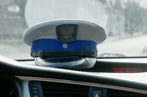 Na kolorowym zdjęciu widoczna policyjna czapka na desce rozdzielczej radiowozu.