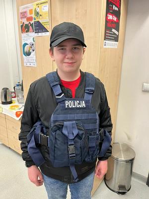 Chłopiec w kamizelce taktycznej z napisem Policja