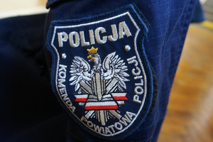 Naszywka na policyjnym mundurze z białym orłem w koronie, pod nim wstęga biało-czerwona. Wokół napis Policja Komenda Powiatowa Policji.