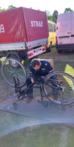 Na kolorowym zdjęciu widoczny policjant znakujący rower.