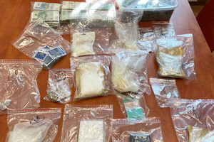 Na zdjęciu widoczne środki odurzające w plastikowych torebkach oraz pliki banknotów rozłożone na stole.