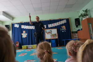 Policjant pokazuje dzieciom zielony klocek.