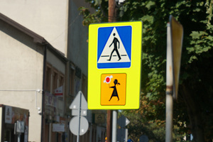 Na zdjęciu widoczny pionowy znak drogowy: przejście dla pieszych i tak zwana Agatka, czyli znak, który wskazuje, że przejście dla pieszych jest szczególnie uczęszczane przez dzieci.