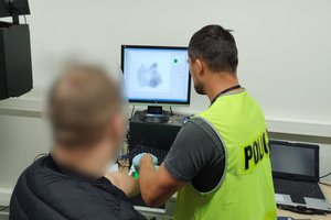 Technik kryminalistyki przeprowadza czynności z zatrzymanym mężczyzną.