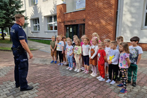 Umundurowany policjant prowadzi spotkanie z dziećmi.