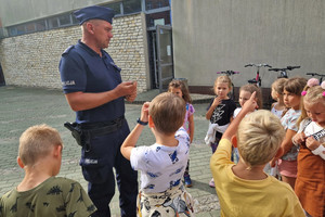 Umundurowany policjant prowadzi spotkanie z dziećmi.