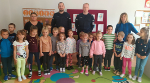 Na zdjęciu grupowym widoczni dwaj umundurowani policjanci oraz dzieci i opiekunowie.