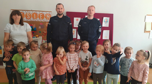 Na zdjęciu grupowym widoczni dwaj umundurowani policjanci oraz dzieci i opiekunowie.