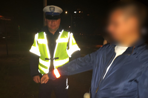 Na zdjęciu widoczny umundurowany policjant przekazujący mężczyźnie odblask.