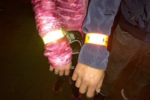 Na zdjęciu widoczne ręce kobiety i mężczyzny, na których założone są opaski odblaskowe.