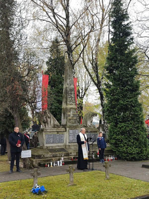 Na zdjęciu widoczny ksiądz przemawiający przed Pomnikiem Niepodległości.