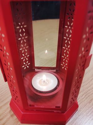 Na zdjęciu widoczny lampion z zapaloną wewnątrz świeczką.
