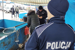 Na zdjęciu widoczni policjanci kontrolujący stoisko z żywymi rybami.