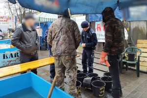 Na zdjęciu widoczni policjanci kontrolujący stoisko z żywymi rybami.