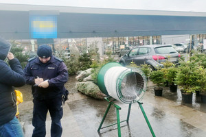 Na zdjęciu widoczny policjant, który kontroluje punkt sprzedaży drzewek.