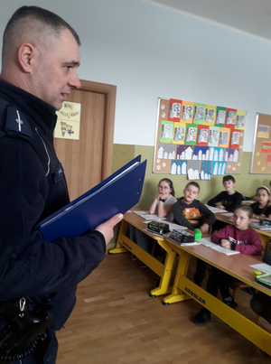 Na zdjęciu widoczny policjant, który prowadzi prelekcję dla dzieci.