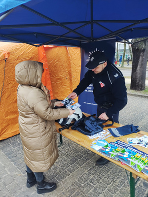 Na zdjęciu widoczny policjant, który przekazuje kobiecie ulotki.