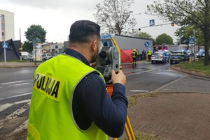 Na zdjęciu widoczne miejsce śmiertelnego potrącenia. Umundurowany policjant wykonuje pomiar tachimetrem.