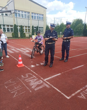 Na zdjęciu widoczni policjanci i dziewczynka jadąca rowerem.