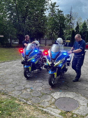 Na zdjęciu widoczne dziecko siedzące na policyjnym motocyklu. Obok stoi policjant.