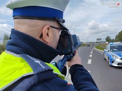 Na zdjęciu widoczny policjant, który mierzy prędkość pojazdu.