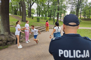 Na zdjęciu widoczny policjant, który kibicuje biegnącym dzieciom.