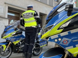 Zdjęcie kolorowe przedstawiające umundurowanego policjanta obok motocykli policyjnych.