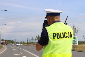 Na zdjęciu widoczny policjant, którzy mierzy prędkość pojazdu.