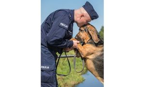 Na zdjęciu widoczny policjant całujący w głowę psa.