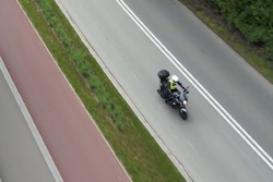 Na zdjęciu widok z lotu ptaka na jadący jezdnią motocykl.