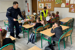 Na zdjęciu widoczni policjanci, którzy rozdają dzieciom odblaski.