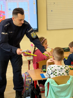 Na zdjęciu widoczny policjant, który rozdaje dzieciom odblaski.