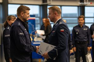 Zastępca Komendanta Wojewódzkiego Policji w Katowicach młodszy inspektor Radosław Kacprzak gratuluje młodszemu aspirantowi Piotr4owi Grabowskiemu.