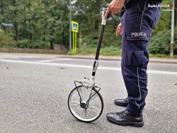 Na zdjęciu widoczny częściowo policjant, który wykonuje czynności na jezdni.