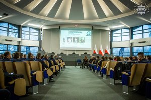 Na zdjęciu sala konferencyjna, w niej siedzący na krzesłach mundurowi, pośrodku wyświetlony slajd Konferencja.