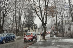 Na zdjęciu widoczny padający śnieg oraz ulica, którą jadą pojazdy.