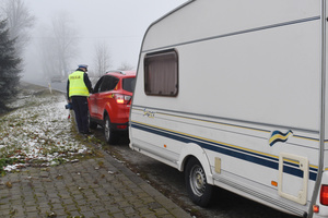 Na zdjęciu widoczny policjant podczas kontroli drogowej pojazdu.