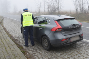 Na zdjęciu widoczny policjant podczas kontroli drogowej pojazdu.