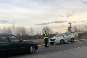 Na zdjęciu widoczny policjant oraz dwa samochody jadące z przeciwnych kierunków.