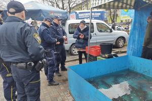 Na zdjęciu widoczni policjanci i strażnicy miejscy, którzy kontrolują stoisko z karpiami.