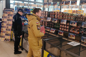 Na zdjęciu widoczny policjant oraz strażak podczas kontroli stoiska z fajerwerkami.