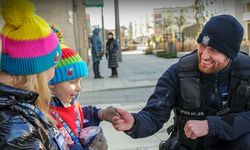 Na zdjęciu widać policjanta i dwie dziewczynki. Policjant wita się uściskiem dłoni z jedną.