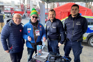 Na zdjęciu widoczni dwaj policjanci oraz wolontariusz i mężczyzna stojący obok niego.