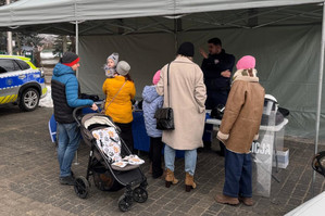 Na zdjęciu widoczne stoisko profilaktyczne oraz policjant i osoby stojące przy stoisku.